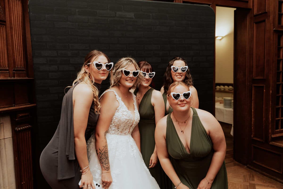 Gäste machen mit einer Herzchenbrille Fotos in einer Fotobox